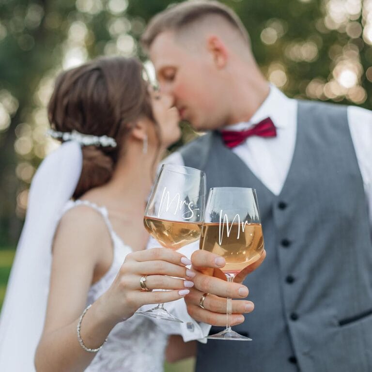 Bride and groom toasting with personalized Mr and Mrs wine glasses.